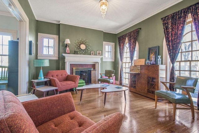 living area featuring a brick fireplace, hardwood / wood-style floors, and ornamental molding