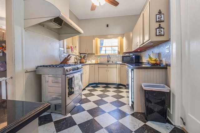 kitchen featuring sink, backsplash, ventilation hood, gas range, and cream cabinetry