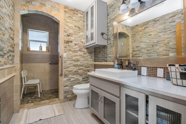 bathroom featuring toilet, vanity, and tiled shower