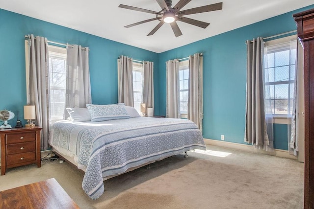 bedroom featuring ceiling fan, light colored carpet, and multiple windows