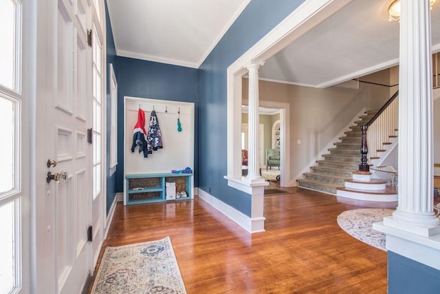 foyer entrance with crown molding, wood-type flooring, and ornate columns