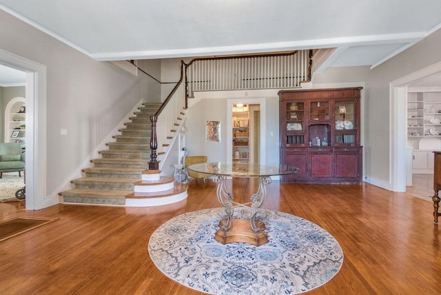 entrance foyer with ornamental molding and hardwood / wood-style floors