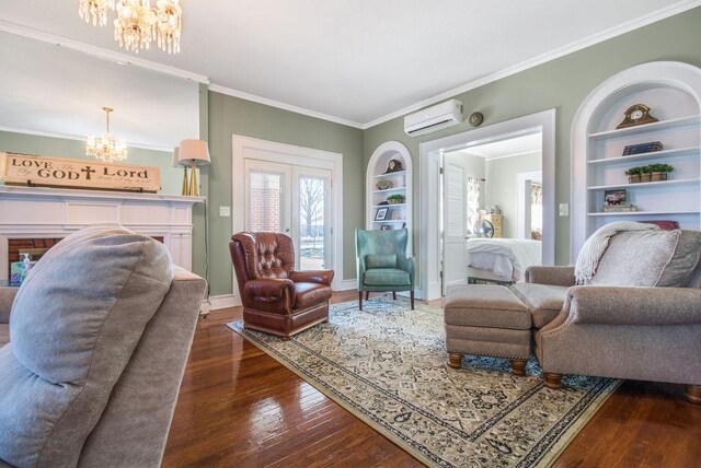 living room with an AC wall unit, built in shelves, dark hardwood / wood-style flooring, a chandelier, and crown molding