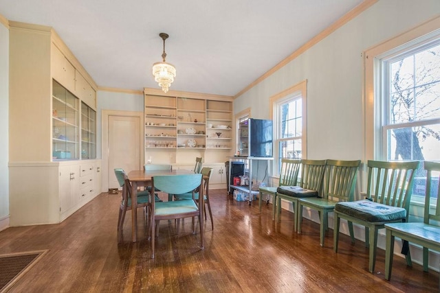 dining area with dark wood-type flooring, plenty of natural light, crown molding, and a chandelier