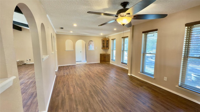 empty room with ceiling fan, a textured ceiling, dark hardwood / wood-style floors, and crown molding