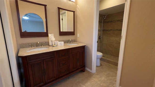 bathroom featuring toilet, tiled shower, and vanity