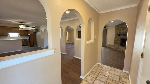 hall with light hardwood / wood-style floors, a textured ceiling, and crown molding