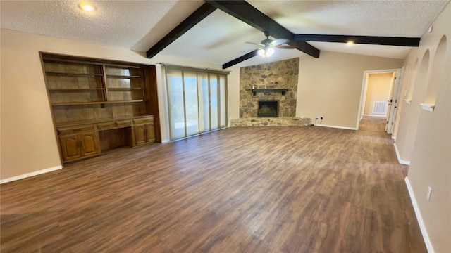 unfurnished living room with ceiling fan, dark hardwood / wood-style flooring, lofted ceiling with beams, a fireplace, and a textured ceiling