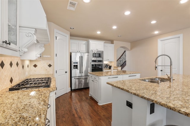 kitchen featuring appliances with stainless steel finishes, white cabinetry, sink, an island with sink, and light stone counters