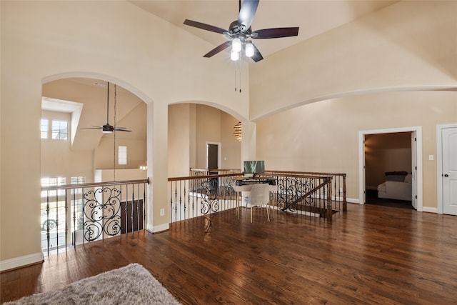 empty room with dark wood-type flooring, high vaulted ceiling, and ceiling fan