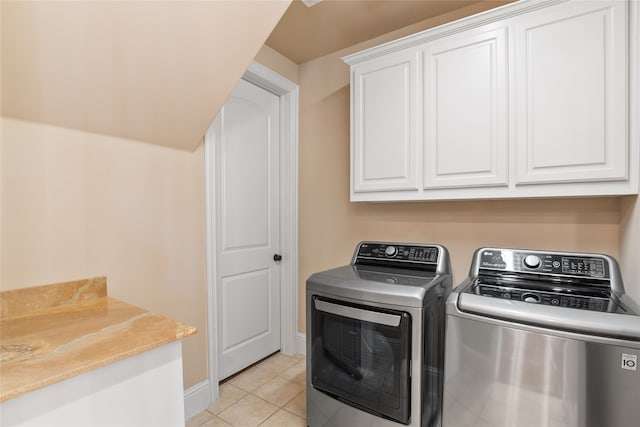 washroom with light tile patterned flooring, cabinets, and washing machine and clothes dryer