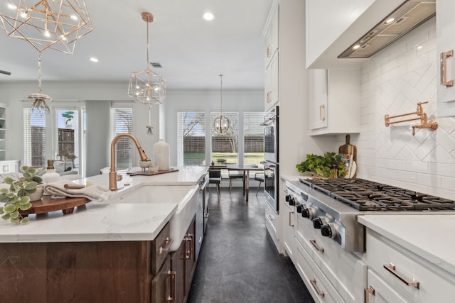 kitchen with white cabinetry, stainless steel appliances, tasteful backsplash, light stone countertops, and decorative light fixtures