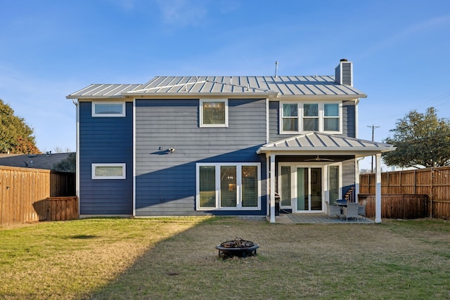 back of house with a yard and an outdoor fire pit