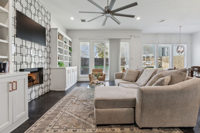 living room with ornamental molding, plenty of natural light, dark hardwood / wood-style floors, and ceiling fan with notable chandelier