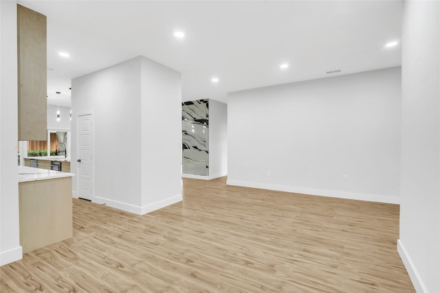 unfurnished living room with sink and light hardwood / wood-style flooring