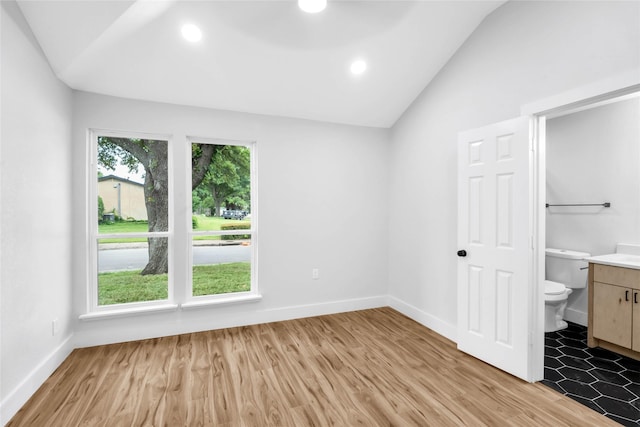 unfurnished bedroom with light hardwood / wood-style floors, ensuite bathroom, and lofted ceiling