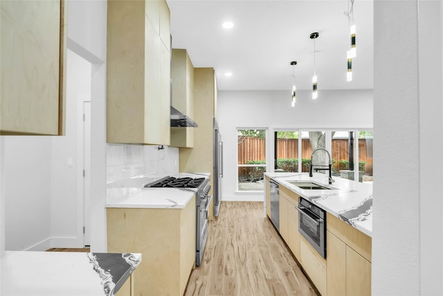 kitchen featuring pendant lighting, appliances with stainless steel finishes, light brown cabinets, sink, and light hardwood / wood-style flooring