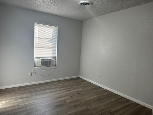 spare room featuring a textured ceiling, dark hardwood / wood-style floors, and cooling unit