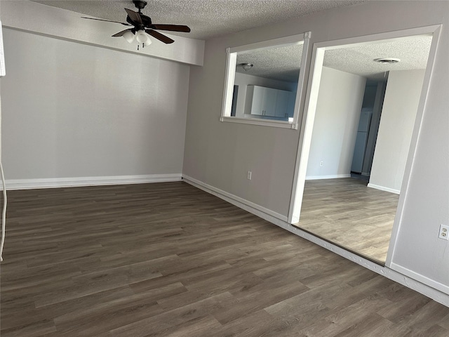 spare room featuring ceiling fan, dark wood-type flooring, and a textured ceiling