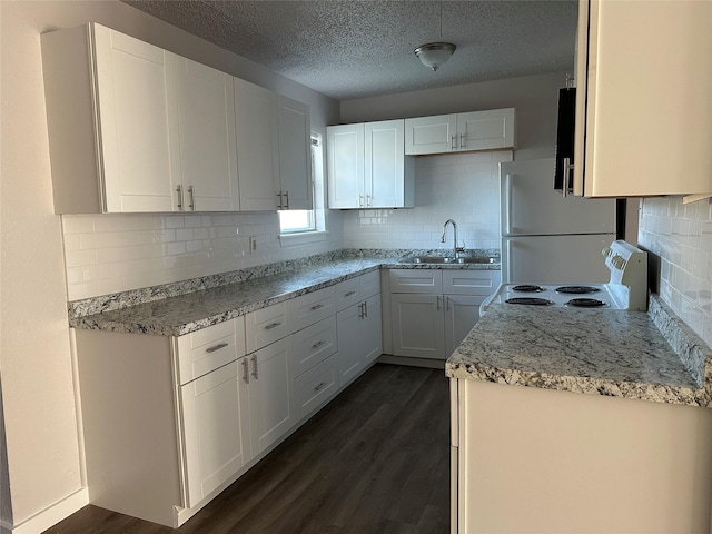 kitchen featuring sink, white cabinetry, backsplash, and white refrigerator