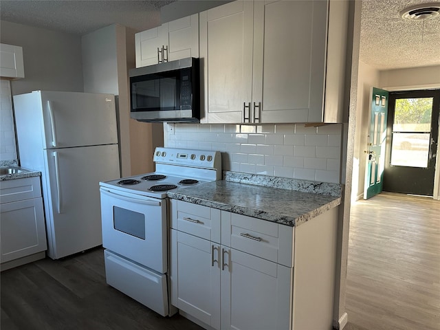 kitchen with white appliances, a textured ceiling, decorative backsplash, white cabinets, and dark hardwood / wood-style flooring