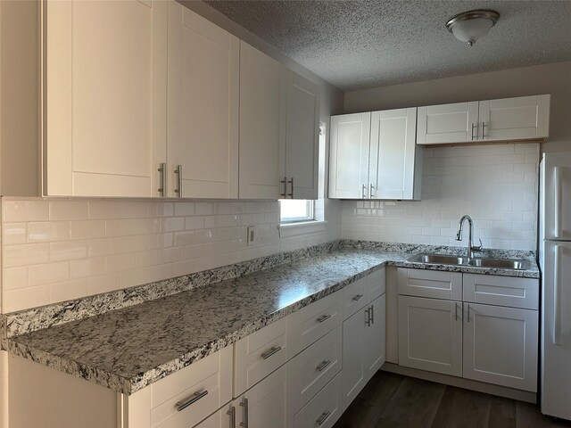 kitchen with sink, white cabinets, light stone countertops, dark hardwood / wood-style floors, and white fridge