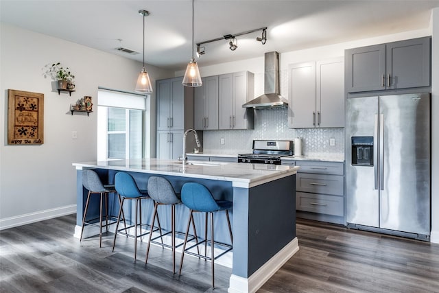 kitchen with a kitchen island with sink, wall chimney range hood, sink, stainless steel appliances, and gray cabinets