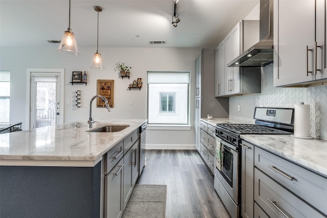 kitchen featuring wall chimney range hood, stainless steel appliances, and gray cabinets