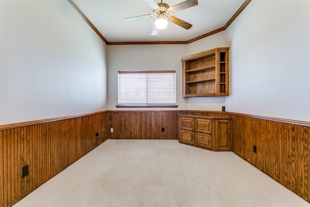 unfurnished office with ceiling fan, ornamental molding, light carpet, and wooden walls