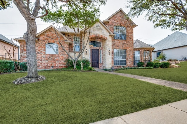 traditional-style house featuring stone siding, brick siding, and a front yard