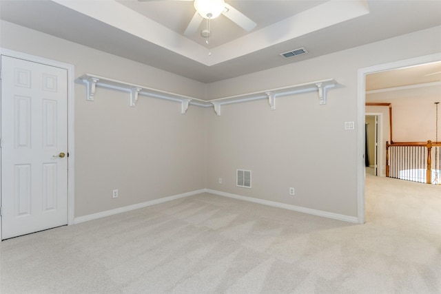 unfurnished room featuring light carpet, ceiling fan, and a tray ceiling