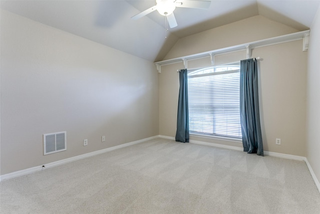 empty room featuring light carpet, visible vents, ceiling fan, and vaulted ceiling