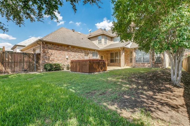 back of house with a yard, a garage, brick siding, fence private yard, and a hot tub