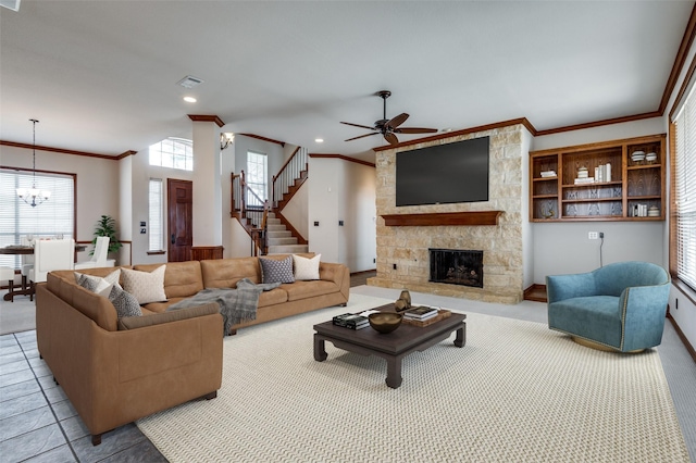 living area with stairway, a stone fireplace, ornamental molding, and visible vents