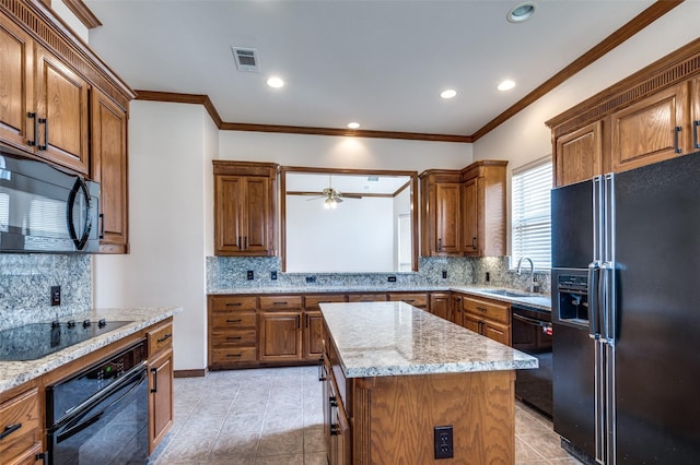 kitchen with visible vents, a sink, black appliances, brown cabinets, and a center island