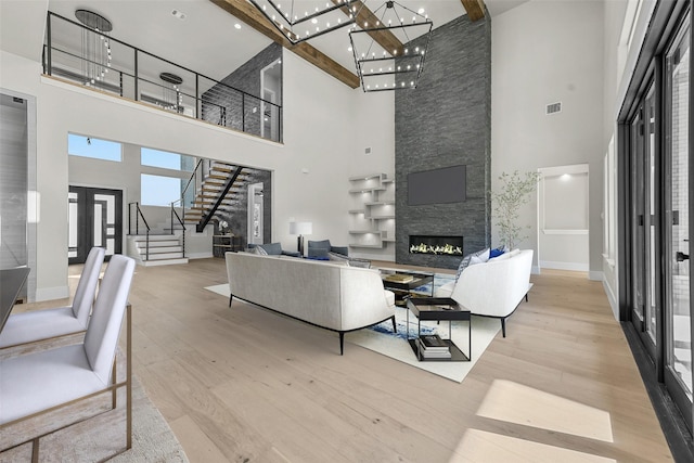 living room featuring light hardwood / wood-style floors, beamed ceiling, and a towering ceiling