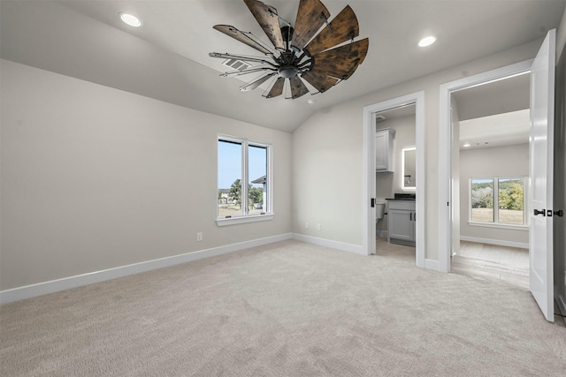 unfurnished bedroom with ceiling fan, multiple windows, connected bathroom, and light carpet