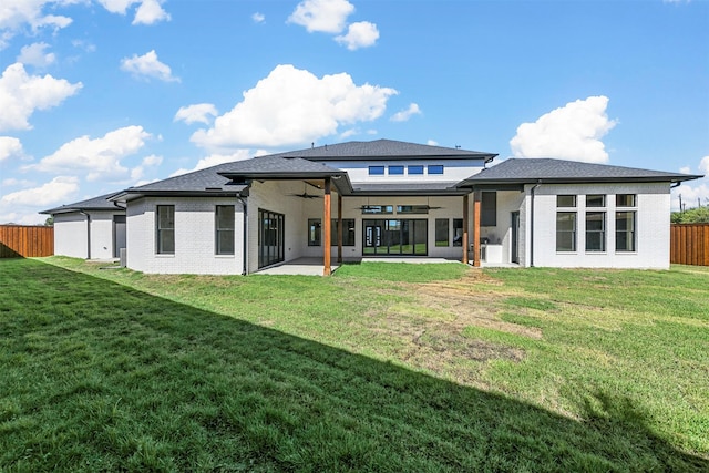 rear view of house with ceiling fan, a yard, and a patio