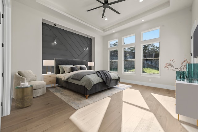 bedroom featuring a high ceiling, hardwood / wood-style flooring, and a raised ceiling