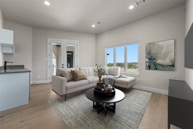 living room featuring sink, light hardwood / wood-style flooring, and french doors