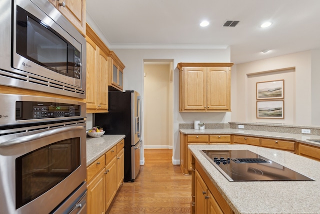 kitchen featuring stainless steel appliances, light brown cabinetry, ornamental molding, light wood-type flooring, and light stone counters