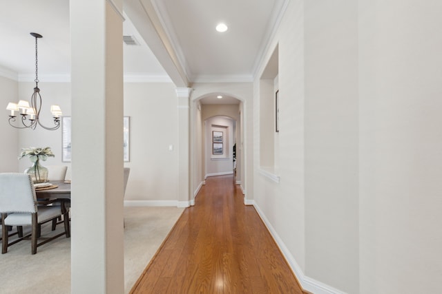 hallway featuring hardwood / wood-style flooring, a chandelier, and ornamental molding