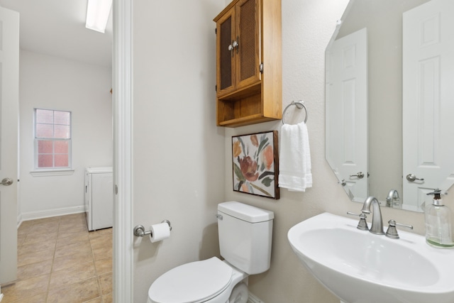 bathroom featuring sink, toilet, washer / dryer, and tile patterned floors