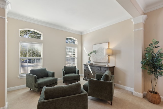 sitting room featuring light colored carpet, crown molding, and ornate columns