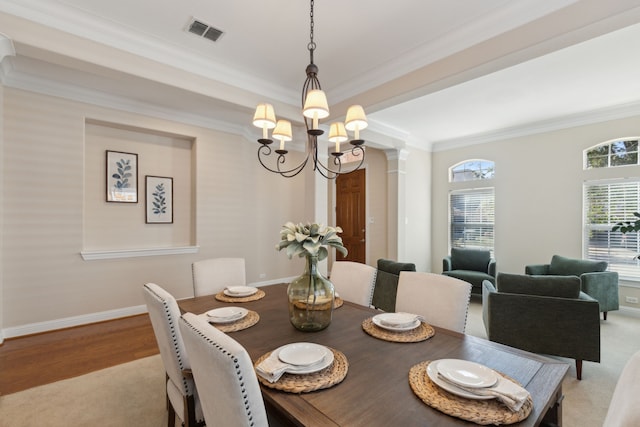 dining area featuring light carpet, an inviting chandelier, ornate columns, and ornamental molding