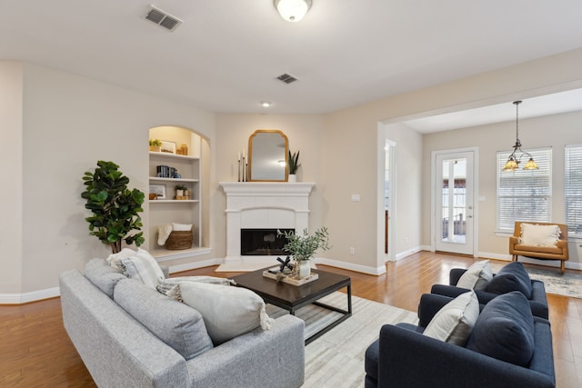 living room featuring built in features and light wood-type flooring