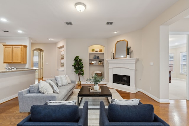 living room featuring built in shelves and light hardwood / wood-style floors