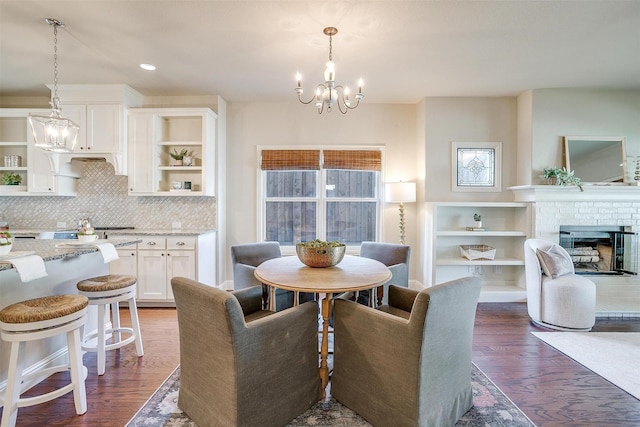 dining area featuring a chandelier, a fireplace, and dark hardwood / wood-style flooring