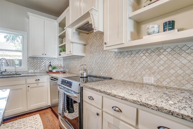 kitchen with light stone countertops, white cabinets, decorative backsplash, sink, and stainless steel electric range oven