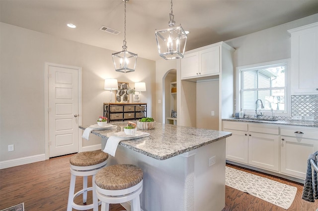 kitchen with light stone counters, sink, and white cabinets